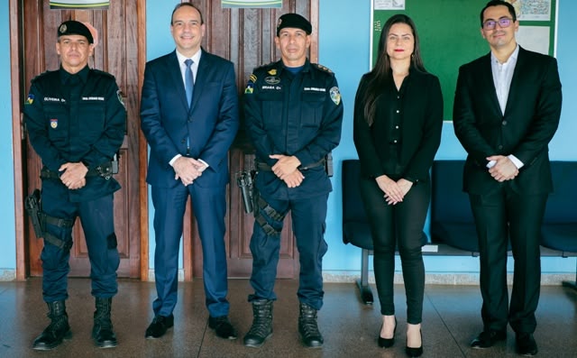 A fotografia mostra 5 pessoas pousando para a câmera que está fotografando, duas dessas pessoas estão vestindo uniformes policiais. 